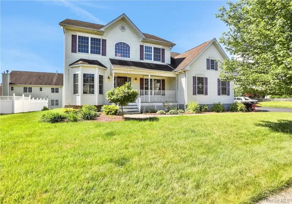 Colonial-style house with a front yard and a porch Colonial-style house with a front yard and a porch