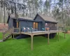 Back of property with a lawn, a wooden deck, and roof with shingles Back of property with a lawn, a wooden deck, and roof with shingles
