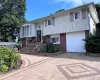 Split-level residence featuring a brick and shingle facade, bay window, and a patterned paver driveway Split-level residence featuring a brick and shingle facade, bay window, and a patterned paver driveway