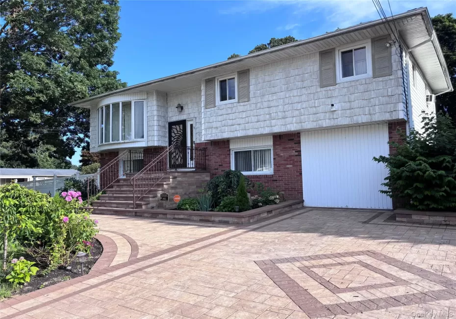 Split-level residence featuring a brick and shingle facade, bay window, and a patterned paver driveway Split-level residence featuring a brick and shingle facade, bay window, and a patterned paver driveway