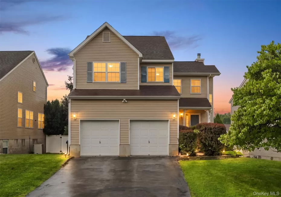 Two-story home featuring light-toned siding, a two-car garage, and a paved driveway Two-story home featuring light-toned siding, a two-car garage, and a paved driveway