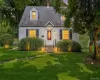 White siding exterior with black shutters, dormer windows, red entry door, and a gray shingled roof White siding exterior with black shutters, dormer windows, red entry door, and a gray shingled roof