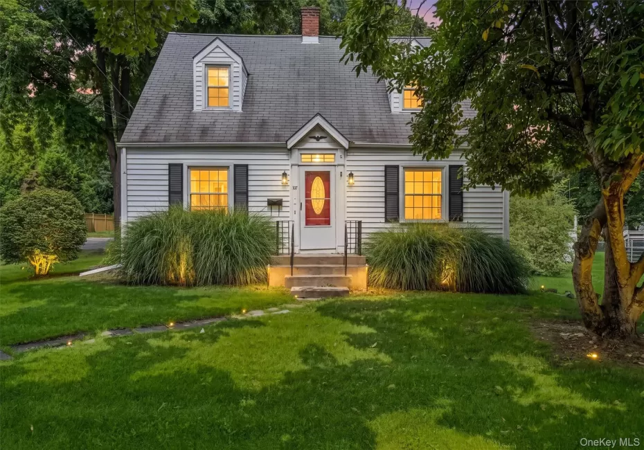 White siding exterior with black shutters, dormer windows, red entry door, and a gray shingled roof White siding exterior with black shutters, dormer windows, red entry door, and a gray shingled roof