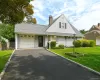 Light-colored siding exterior with a dark entry door, attached garage with panel door, asphalt driveway, and a well-maintained lawn Light-colored siding exterior with a dark entry door, attached garage with panel door, asphalt driveway, and a well-maintained lawn