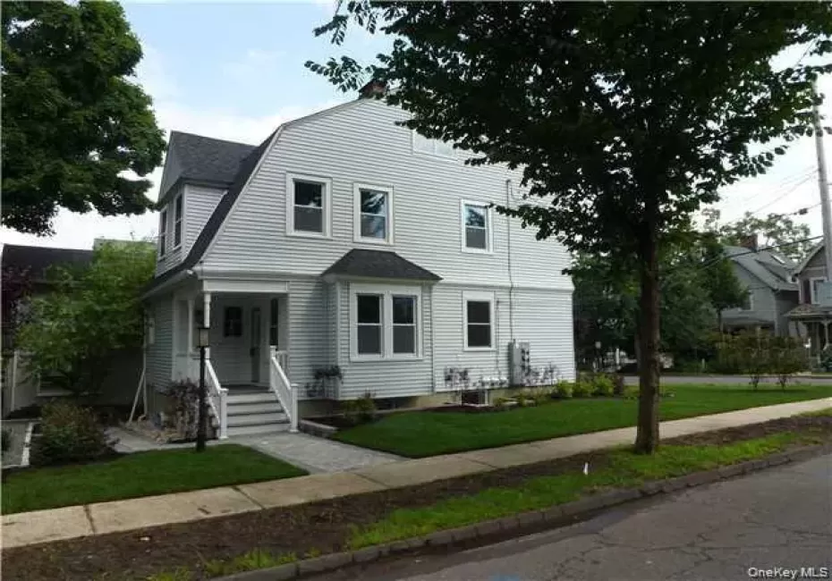 Gambrel roof architecture with white siding, a covered entry porch, and a paved walkway Gambrel roof architecture with white siding, a covered entry porch, and a paved walkway