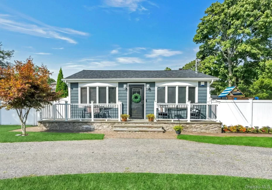 Exterior featuring blue siding, a dark new roof, a front porch with white railings, stone facade detailing, and driveway Exterior featuring blue siding, a dark new roof, a front porch with white railings, stone facade detailing, and driveway