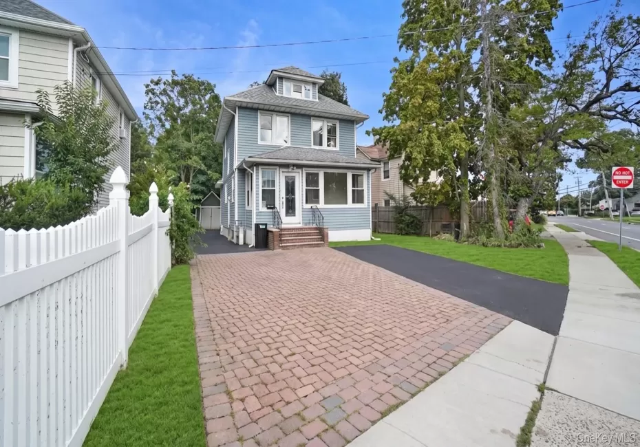 Two-story residence with a covered porch, dormer windows, and a paved driveway Two-story residence with a covered porch, dormer windows, and a paved driveway