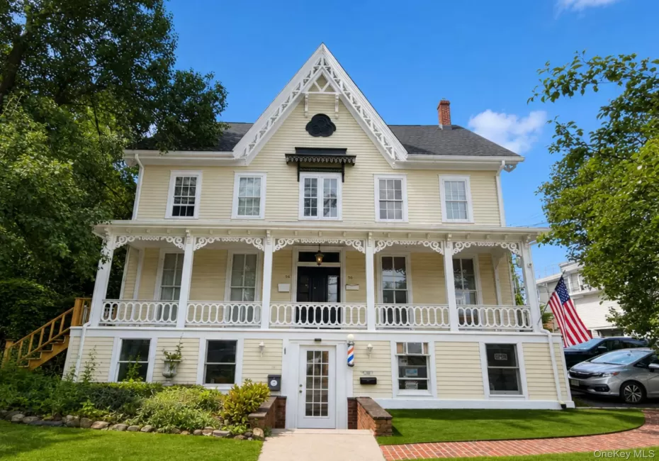Victorian-style exterior with decorative gables, a covered front porch with ornate railings, a brick walkway, and mature landscaping. Edited using AI Victorian-style exterior with decorative gables, a covered front porch with ornate railings, a brick walkway, and mature landscaping. Edited using AI