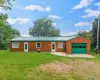 Wood-paneled exterior with a green metal roof, integrated garage featuring a green door, and multiple entry points Wood-paneled exterior with a green metal roof, integrated garage featuring a green door, and multiple entry points