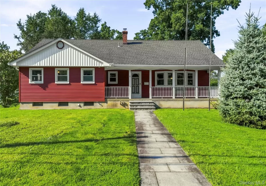 Red-sided residence featuring a covered front porch with white railings, a front-facing gable with vertical siding, and a stone-paved walkway Red-sided residence featuring a covered front porch with white railings, a front-facing gable with vertical siding, and a stone-paved walkway
