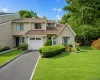 Exterior featuring tan siding, an attached garage, a paved driveway, and manicured landscaping Exterior featuring tan siding, an attached garage, a paved driveway, and manicured landscaping