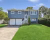 Split-level residence featuring blue siding, white trim, and a two-car garage Split-level residence featuring blue siding, white trim, and a two-car garage