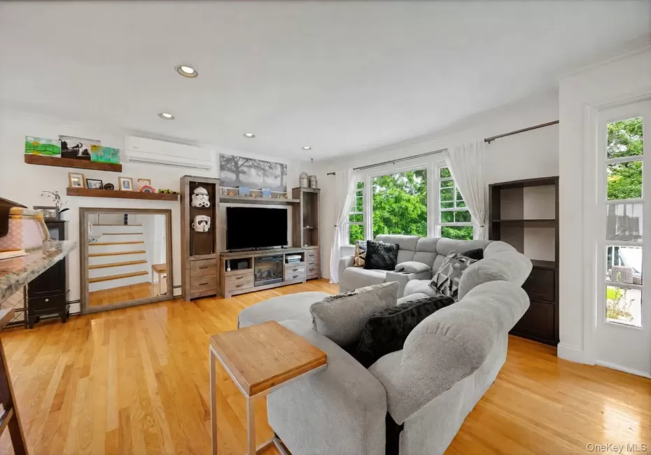Bright living area featuring wood-finish flooring, recessed lighting, and white crown molding Bright living area featuring wood-finish flooring, recessed lighting, and white crown molding