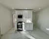 Kitchen featuring backsplash, white cabinetry, sink, and appliances with stainless steel finishes Kitchen featuring backsplash, white cabinetry, sink, and appliances with stainless steel finishes