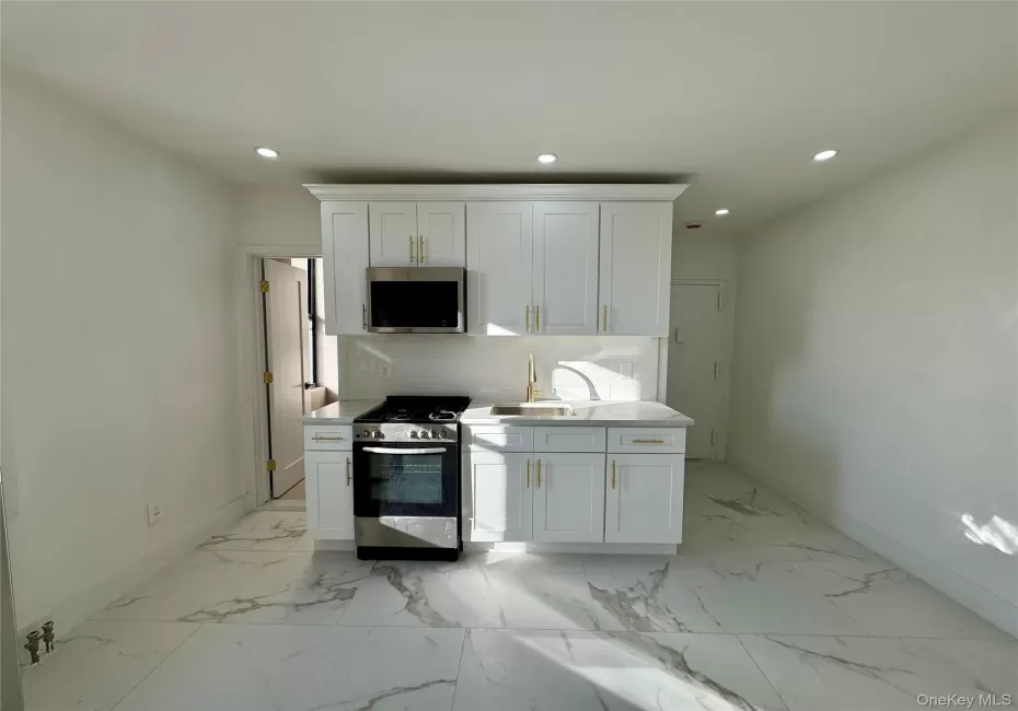 Kitchen featuring backsplash, white cabinetry, sink, and appliances with stainless steel finishes Kitchen featuring backsplash, white cabinetry, sink, and appliances with stainless steel finishes