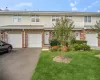 Brick lower facade with white siding, integrated two-car garage, manicured lawn, and established landscaping Brick lower facade with white siding, integrated two-car garage, manicured lawn, and established landscaping