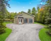 Modern ranch-style home featuring a four-car garage with frosted glass doors, a stone facade accent, and a light green exterior Modern ranch-style home featuring a four-car garage with frosted glass doors, a stone facade accent, and a light green exterior