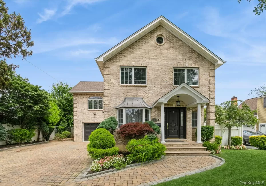 View of front of home with brick siding, decorative driveway, an attached garage, and a front yard View of front of home with brick siding, decorative driveway, an attached garage, and a front yard