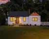 Front exterior featuring white vertical siding, dark framed windows, a dark shingle roof, a wood-paneled entry accent, and a white picket fence Front exterior featuring white vertical siding, dark framed windows, a dark shingle roof, a wood-paneled entry accent, and a white picket fence