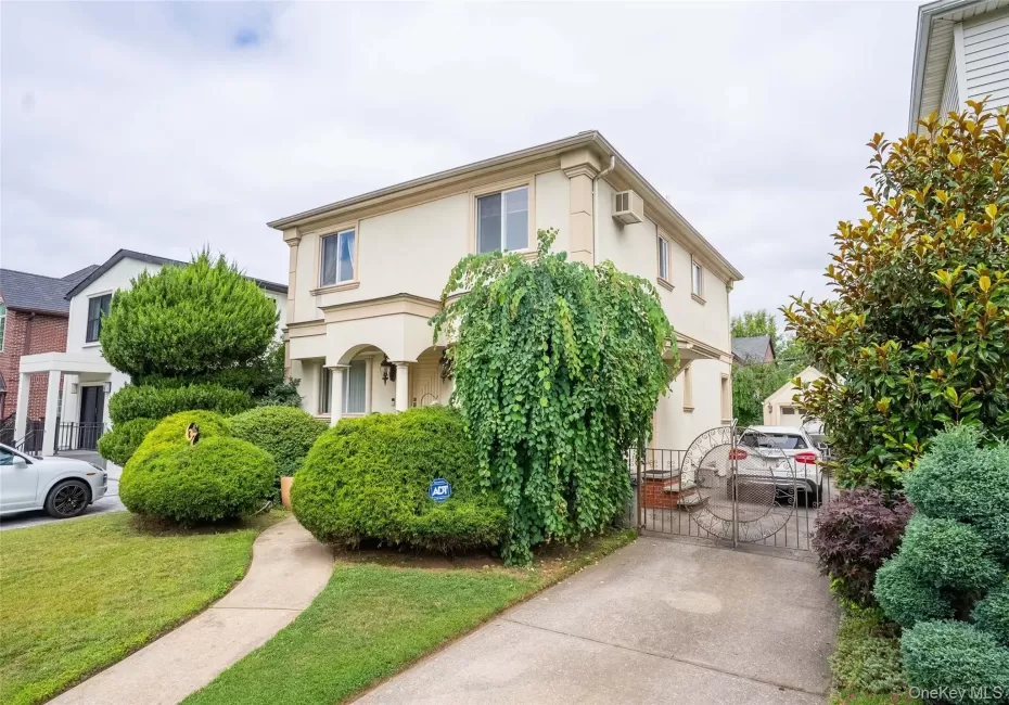 View of front of house with stucco siding, a wall mounted AC, and a front lawn View of front of house with stucco siding, a wall mounted AC, and a front lawn