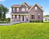 Brown siding exterior with white trim, covered front porch, front entry door with sidelights, and a sloped front lawn Brown siding exterior with white trim, covered front porch, front entry door with sidelights, and a sloped front lawn