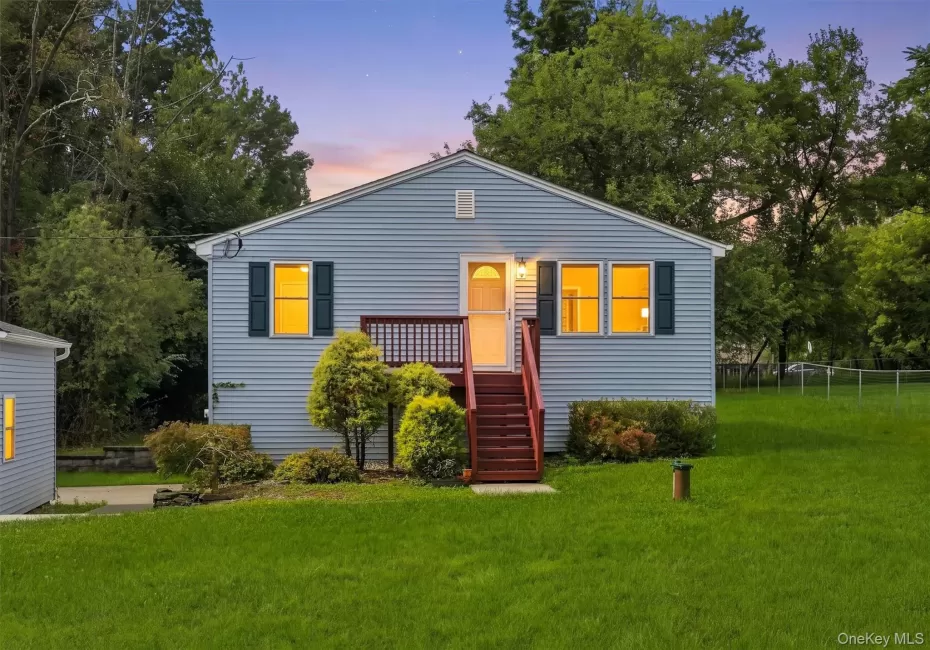 Light blue horizontal siding exterior, dark shutters, red wood-finish porch and stairs, green landscaping, and a detached shed Light blue horizontal siding exterior, dark shutters, red wood-finish porch and stairs, green landscaping, and a detached shed