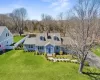 Cape cod home featuring a front yard, roof with shingles, fence, and a chimney Cape cod home featuring a front yard, roof with shingles, fence, and a chimney