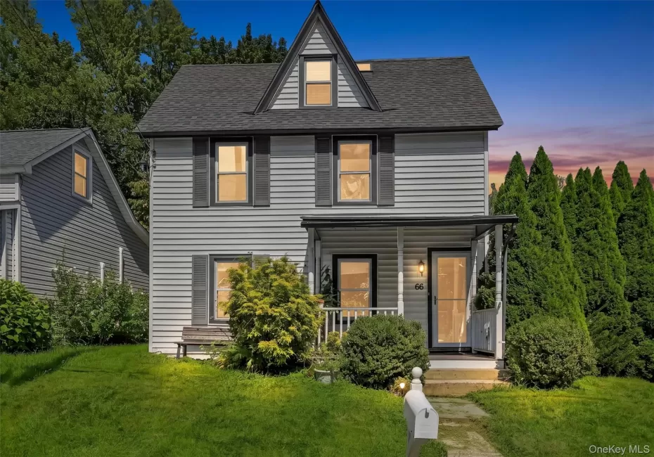 Two-story residence featuring light gray siding, dark gray shutters, and a covered front porch Two-story residence featuring light gray siding, dark gray shutters, and a covered front porch
