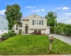 Split-level residence featuring light-colored siding, a front entry with an arched transom, and a lower-level window with a flower bed Split-level residence featuring light-colored siding, a front entry with an arched transom, and a lower-level window with a flower bed