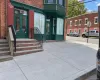Brick facade building featuring a green double-door entry, a bay window, and a concrete walkway Brick facade building featuring a green double-door entry, a bay window, and a concrete walkway