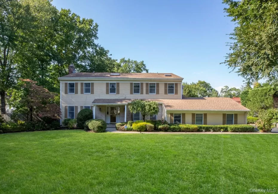 Colonial inspired home featuring a front lawn, a porch, and a chimney Colonial inspired home featuring a front lawn, a porch, and a chimney