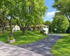 Split-level residence featuring a white and stone exterior, attached garage, paved driveway, and mature landscaping Split-level residence featuring a white and stone exterior, attached garage, paved driveway, and mature landscaping