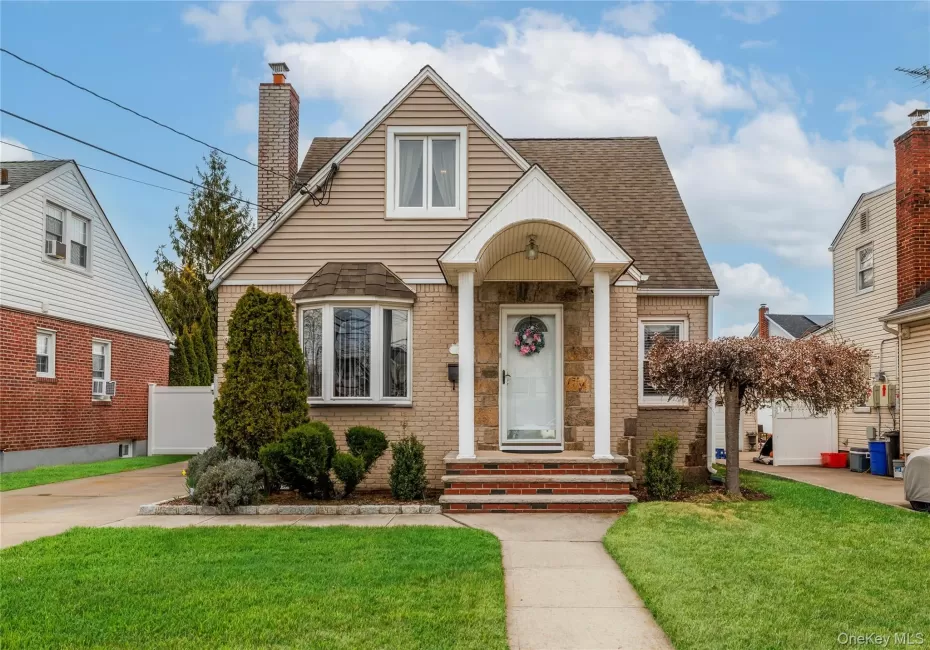 Cape Cod with a chimney, fence, brick siding, a front lawn, and a shingled roof Cape Cod with a chimney, fence, brick siding, a front lawn, and a shingled roof