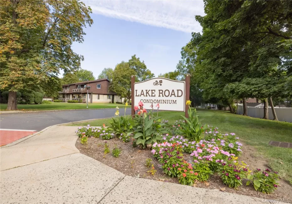 Lake Road Condominium entrance sign with a landscaped flower bed, mature trees, and a two-story building in the background Lake Road Condominium entrance sign with a landscaped flower bed, mature trees, and a two-story building in the background