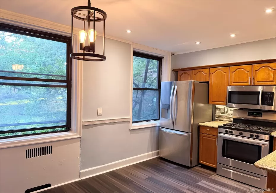 Wood-finish flooring, recessed lighting, and a contemporary ceiling fixture Wood-finish flooring, recessed lighting, and a contemporary ceiling fixture