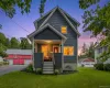 Two-story residence featuring a covered front porch, dark siding, and a red detached garage with two bays Two-story residence featuring a covered front porch, dark siding, and a red detached garage with two bays