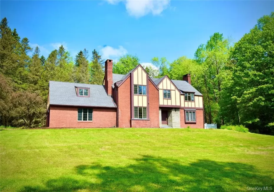 English style brick Tudor House with a chimney, board and batten siding, and a front lawn English style brick Tudor House with a chimney, board and batten siding, and a front lawn