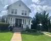 White siding exterior with a front gable, bay windows, and a dark paneled entry door White siding exterior with a front gable, bay windows, and a dark paneled entry door