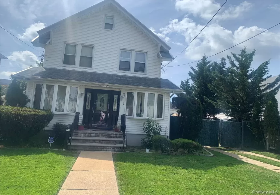 White siding exterior with a front gable, bay windows, and a dark paneled entry door White siding exterior with a front gable, bay windows, and a dark paneled entry door