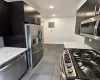 Kitchen featuring dark wood-finish cabinetry, stainless steel appliances, marble-finish countertops, and tile flooring Kitchen featuring dark wood-finish cabinetry, stainless steel appliances, marble-finish countertops, and tile flooring