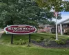 Manicured lawn with mature trees and a dedicated landscape bed with sign for the complex Manicured lawn with mature trees and a dedicated landscape bed with sign for the complex
