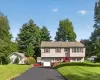 Split-level residence featuring a two-car garage, red entry door, and red window shutters Split-level residence featuring a two-car garage, red entry door, and red window shutters
