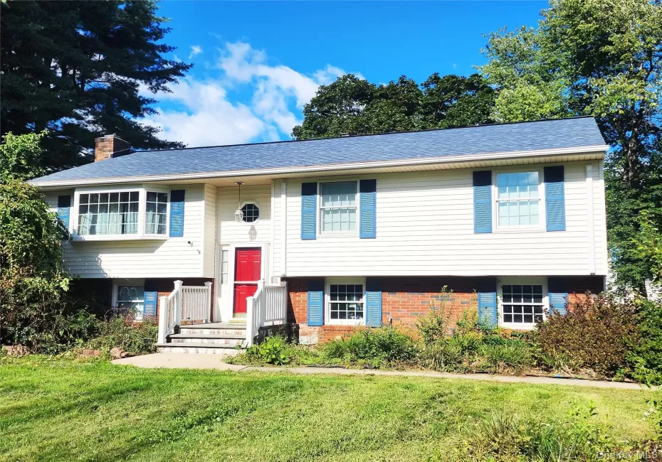 Bi-level home featuring a bay window, vinyl siding, brick accent facade, and a prominent red entry door Bi-level home featuring a bay window, vinyl siding, brick accent facade, and a prominent red entry door