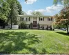 Split-level residence featuring beige siding with dark red window shutters and a matching front door Split-level residence featuring beige siding with dark red window shutters and a matching front door