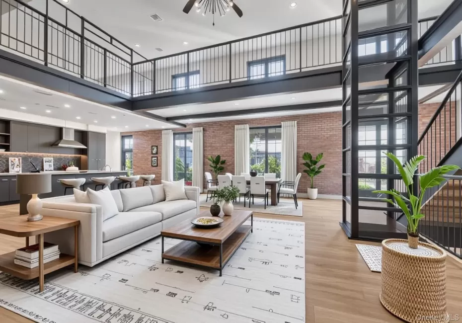 Living room featuring a high ceiling, brick wall, a ceiling fan, light wood-type flooring, and recessed lighting Living room featuring a high ceiling, brick wall, a ceiling fan, light wood-type flooring, and recessed lighting