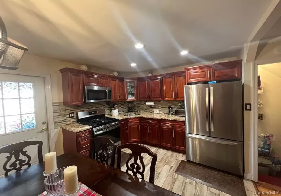 Kitchen featuring wood-finish cabinetry, stainless steel appliances, granite countertops, and a tiled backsplash Kitchen featuring wood-finish cabinetry, stainless steel appliances, granite countertops, and a tiled backsplash
