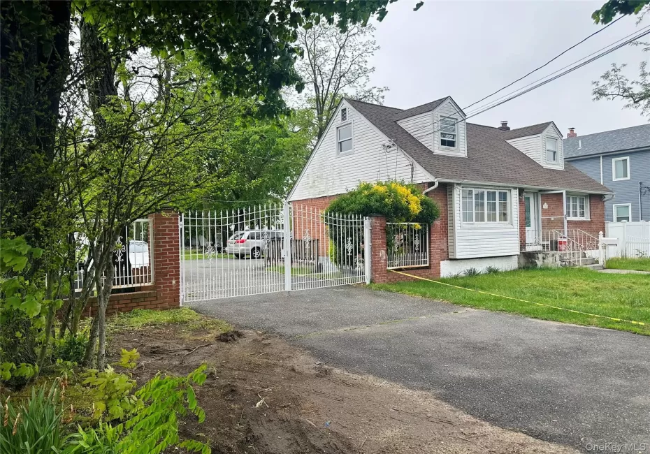 View of front of home with brick siding, a shingled roof, fence private yard, aphalt driveway, and a gate View of front of home with brick siding, a shingled roof, fence private yard, aphalt driveway, and a gate