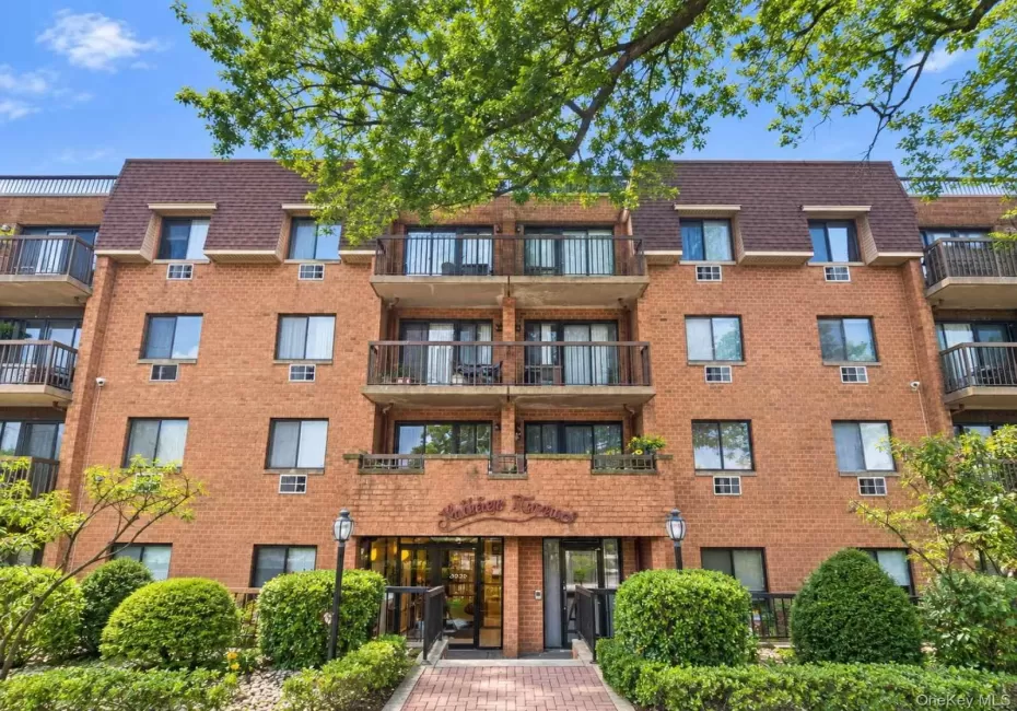 Brick exterior building with multiple private balconies, a mansard roof, and an inviting entryway with a paved walkway Brick exterior building with multiple private balconies, a mansard roof, and an inviting entryway with a paved walkway