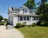 View of front of house with a shingled roof, a front yard, and a chimney View of front of house with a shingled roof, a front yard, and a chimney