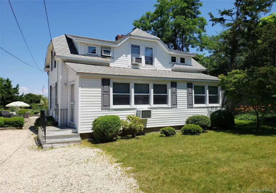 View of front of house with a shingled roof, a front yard, and a chimney View of front of house with a shingled roof, a front yard, and a chimney